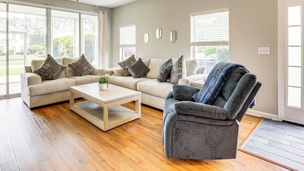 A living room with two sofas, a coffee table, and a recliner. There are large windows with blinds, a ceiling fan, and a door to the right. - < 1 Mi to Legends Golf Resort: Condo w/ Pool! (Myrtle Beach)