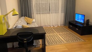 Une chambre moderne comprenant un lit, un bureau avec une chaise, une télévision et un tapis à motifs.