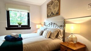 Une chambre à coucher avec un lit, une table de chevet, une lampe, une fenêtre et un tableau au mur.