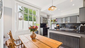 A modern kitchen with a wooden dining table, a vase of flowers, and a large window. - Host Stay Beech Street (Liverpool)