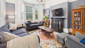 A living room with a sofa, armchairs, a coffee table, a fireplace, a television, and a bookshelf. - Host Stay Beech Street (Liverpool)