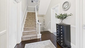 A hallway with a carpeted staircase, a dark wooden dresser, and a wall clock. - Host Stay Beech Street (Liverpool)