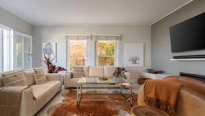 Un salon moderne avec une table basse en verre, des canapés en cuir et un grand téléviseur.