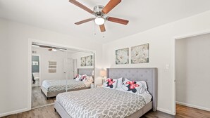 A bedroom with a large bed, a ceiling fan, a mirror, and artwork on the walls. - Spacious Family Friendly House in Central Location (La Puente)