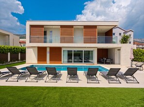 Un bâtiment moderne à deux étages, doté d’une piscine et d’un espace extérieur aménagé pour se détendre.