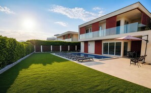 Un bĂątiment moderne Ă deux Ă©tages, dotĂ© dâune piscine, dâun espace extĂ©rieur amĂ©nagĂ© et dâune pelouse bien entretenue.