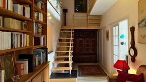Eine Treppe führt zu einer Empore mit einer Holztür und einer Uhr an der Wand.