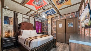 A bedroom with a large bed, a wooden headboard, a bookshelf, and a wardrobe.