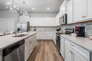 A modern kitchen with white cabinetry, stainless steel appliances, and a wood floor. - Sleeps 25•Game Room•Pool•Free Water Slides (Davenport)