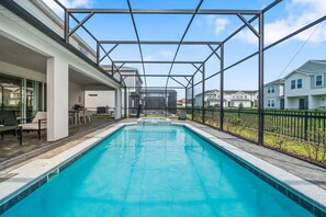 A swimming pool with a covered area, surrounded by a fence, and adjacent to a building with outdoor seating. - Sleeps 25•Game Room•Pool•Free Water Slides (Davenport)