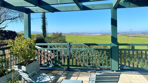 A covered outdoor seating area with a view of a green field and distant landscape.