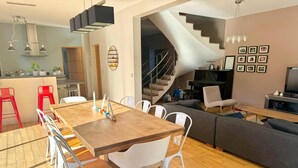 A modern living space with a dining area, a staircase, and a seating area.