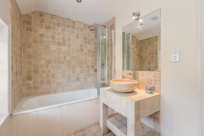 A bathroom with a bathtub, a glass shower enclosure, and a sink with a marble countertop.