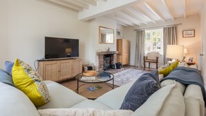 Una sala de estar con sofá, televisión, chimenea y un comedor con mesa y sillas.