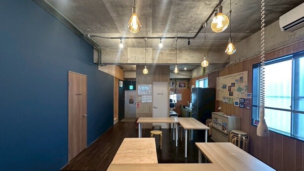 Een modern interieur met een lange houten tafel, hangende pendellampen en uitzicht op zee door grote ramen.