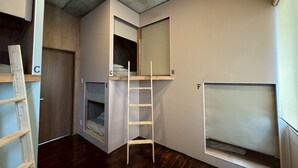 Een kleine kamer met een stapelbed, een ladder en een klein raam.