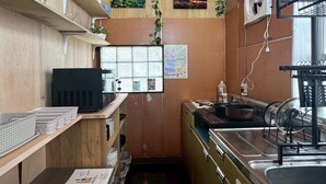 Een kleine keuken met een spoelbak, fornuis en planken met keukengerei.