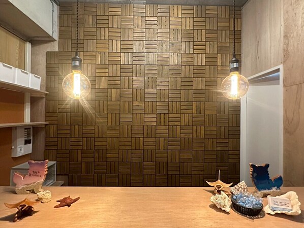 Una habitación con un patrón de pared de madera en espiga, dos lámparas colgantes y una mesa con varios objetos decorativos, incluyendo figuritas y un plato pequeño.