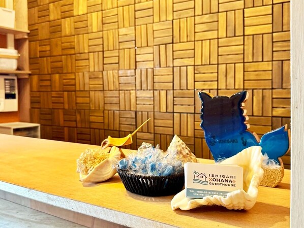 A reception area with a wooden wall, a counter with a business card, a decorative bowl, and a blue ceramic piece.