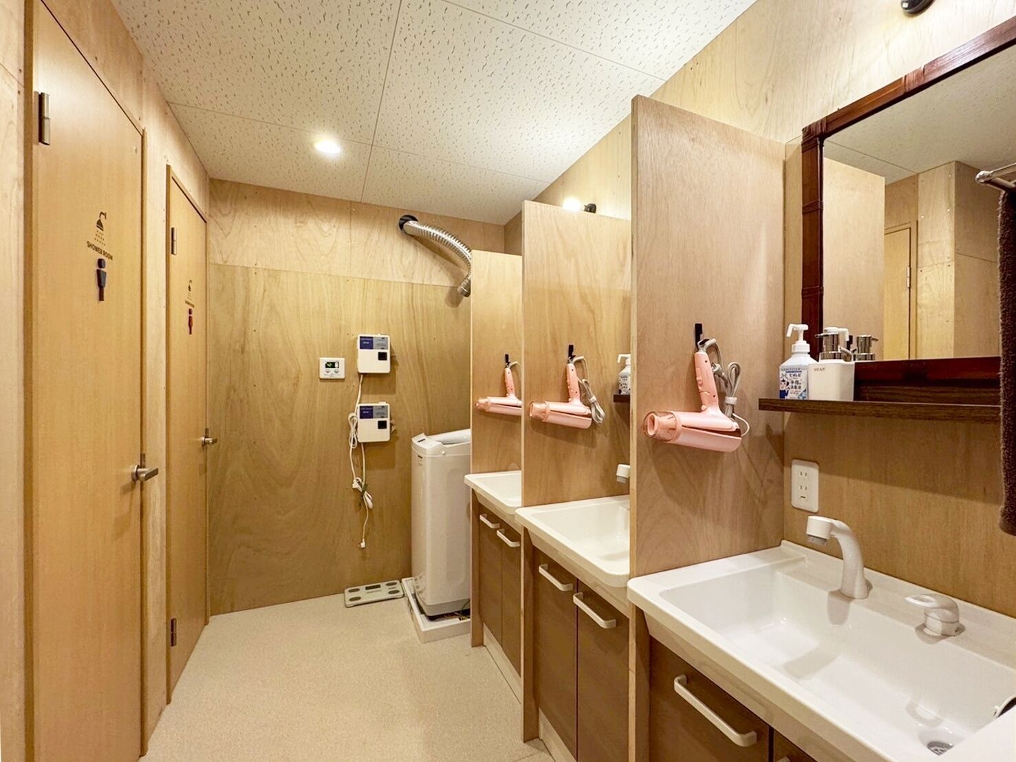 Un baño moderno con paredes de madera, dos lavamanos, un espejo grande y una zona de ducha.