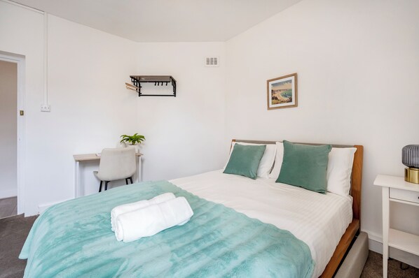 Une chambre bien rangée, avec un lit, un bureau et une chaise.