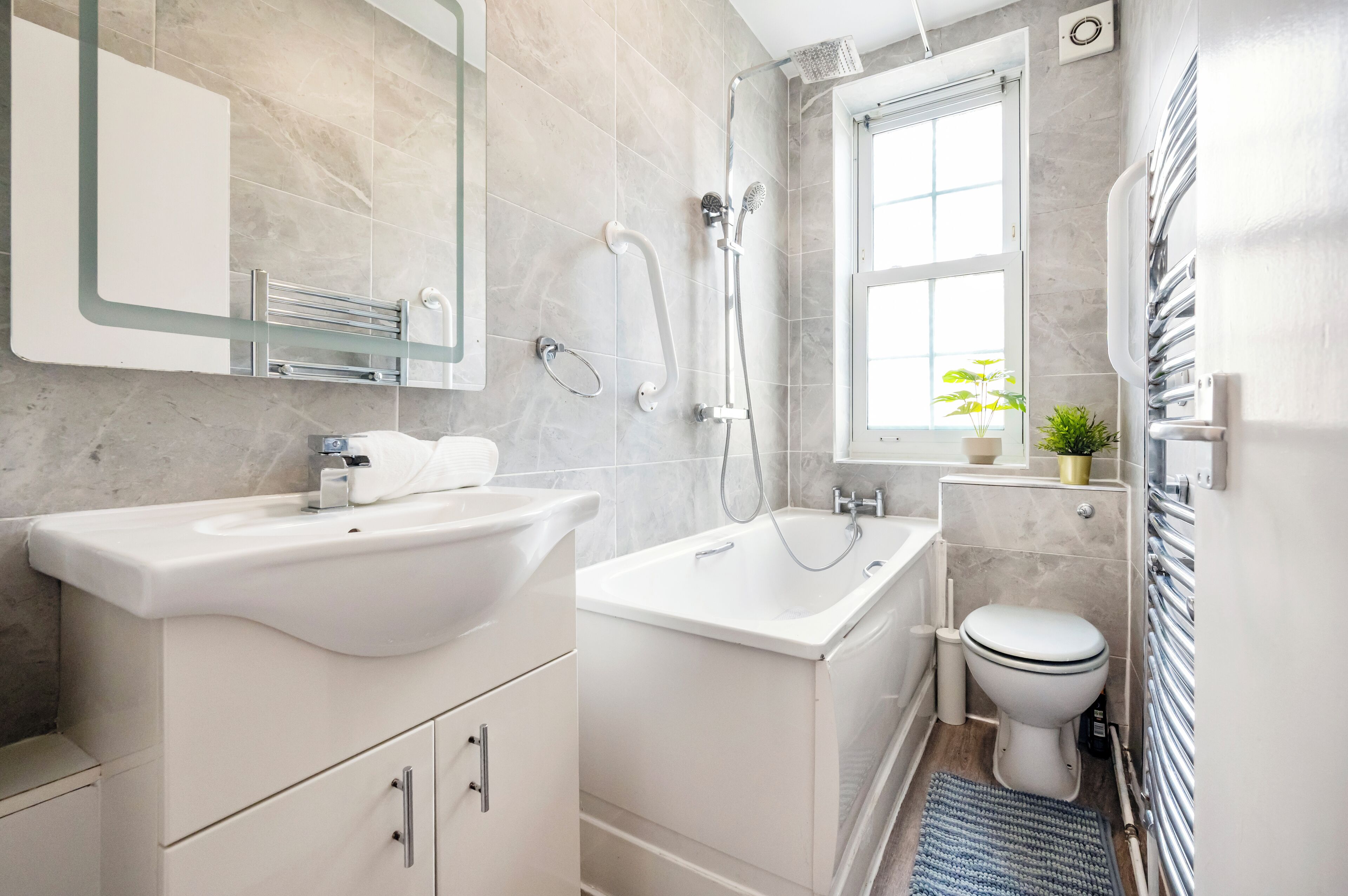 A modern bathroom with a sink, bathtub, and toilet.