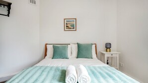 A neatly made bed with a striped blanket, two pillows, and two rolled towels. - Modern London stay near Nothing Hill (London)