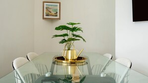 A glass-top table with a gold-colored plant in a pot, surrounded by white chairs. - Modern London stay near Nothing Hill (London)