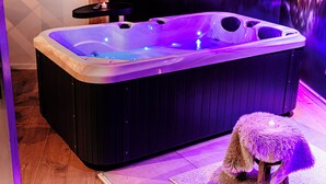 A hot tub with a wooden exterior and a small table on top. - Wellness for two (Ahlen)