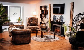 A living room with a fireplace, leather armchairs, a television, and a bookshelf.