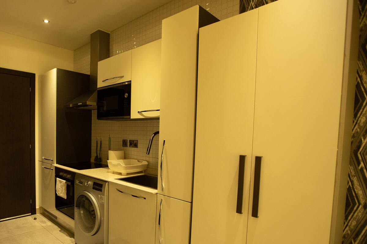 A compact kitchen with a washing machine, a microwave, and a sink.