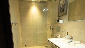 Ein modernes Badezimmer mit Duschkabine aus Glas, Toilette und Waschbecken mit Spiegel darüber.