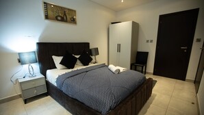 Ein Schlafzimmer mit Bett, Nachttischen, einem Kleiderschrank und einer Tür.
