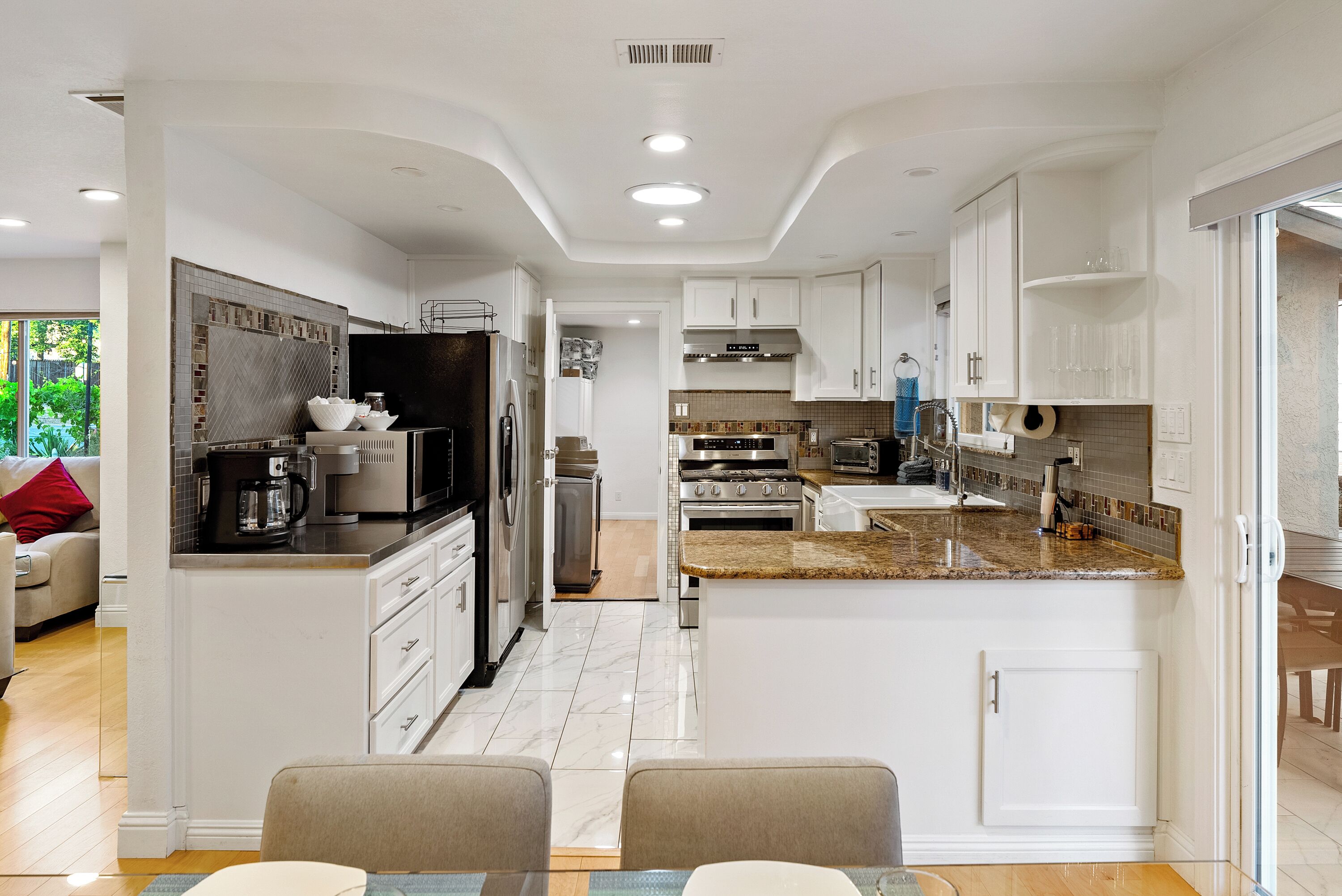 A modern kitchen with white cabinetry, granite countertops, and stainless steel appliances.
