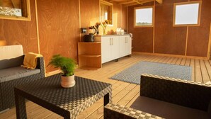 Una habitación acogedora con techo de madera, un sofá, una mesa con planta en maceta y una zona de cocina con armarios y encimera.