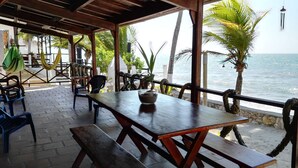 An outdoor patio with wooden tables and benches, overlooking the sea. - Beachfront Cabin With Wi-fi (Tolú)