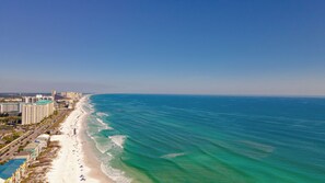 Un paysage urbain côtier avec une plage, des immeubles de grande hauteur et un ciel bleu dégagé.