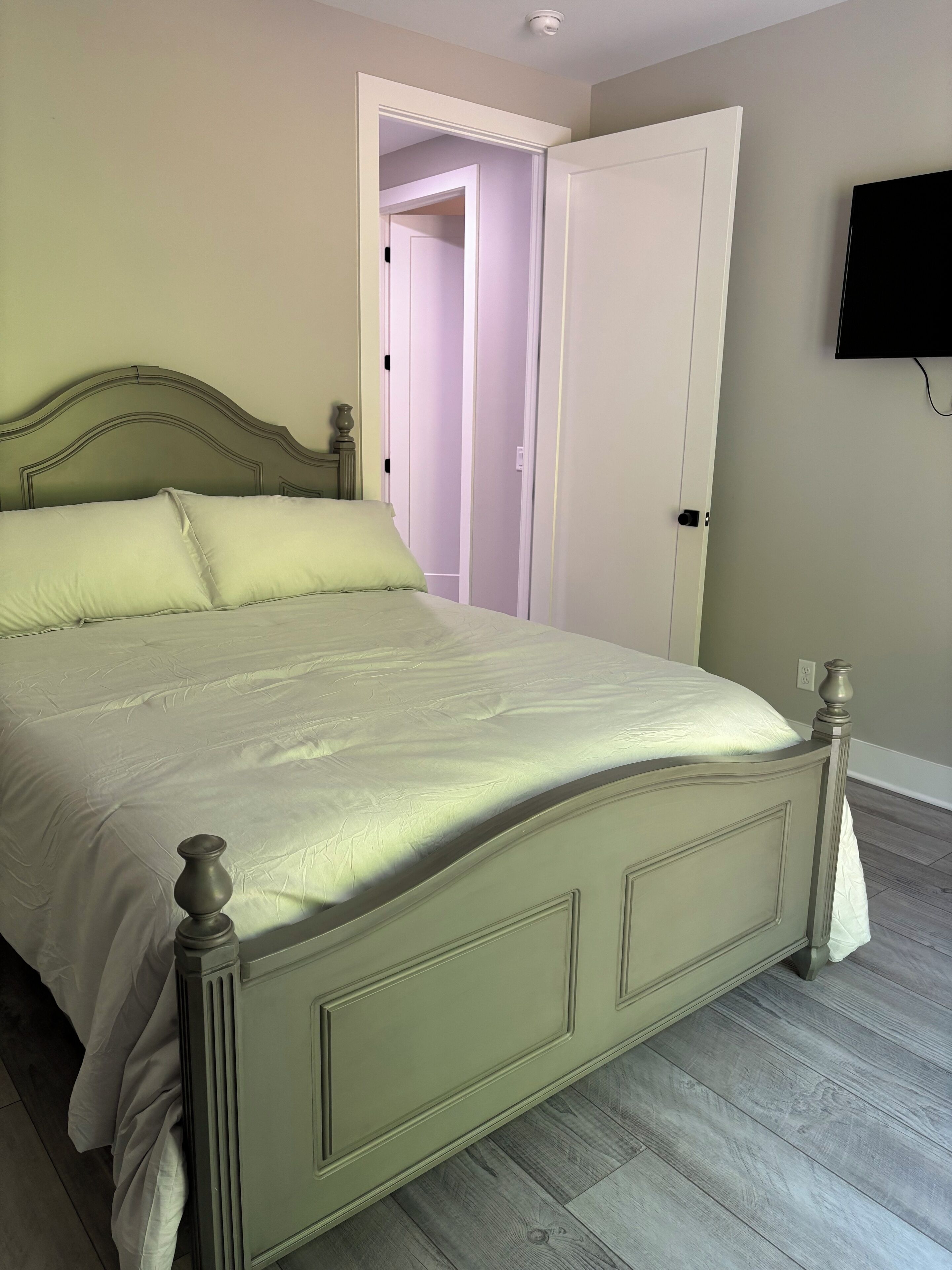 A bed with a headboard, a bedside table, and a wall-mounted TV.