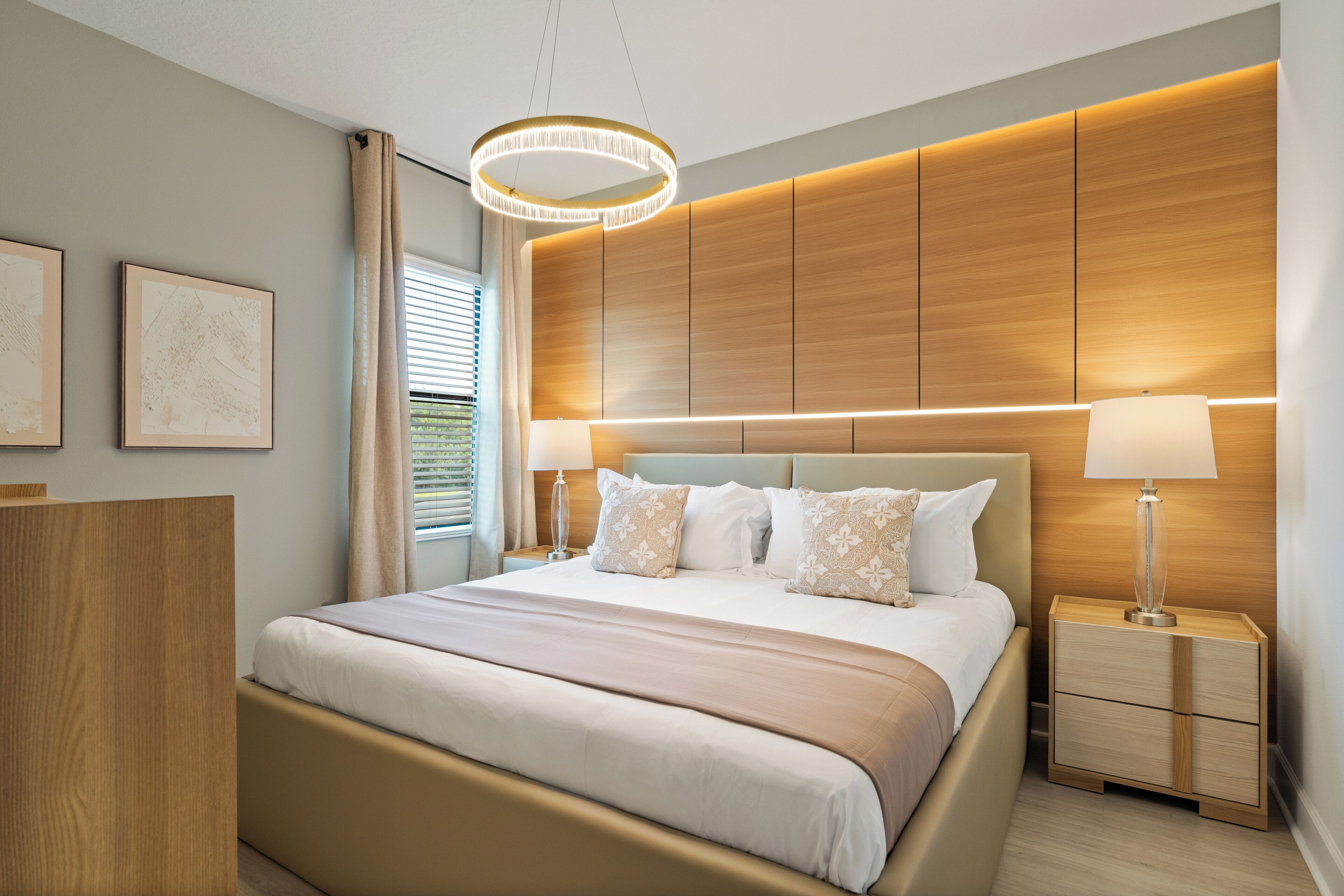 Un dormitorio moderno con una cama grande, cabecera de madera, lámparas de noche y una lámpara de techo.