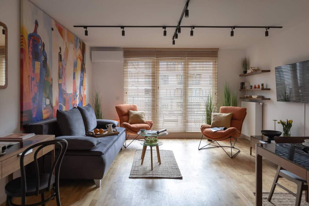 A modern living room with a sofa, two armchairs, a coffee table, and a dining area with a table and chairs.