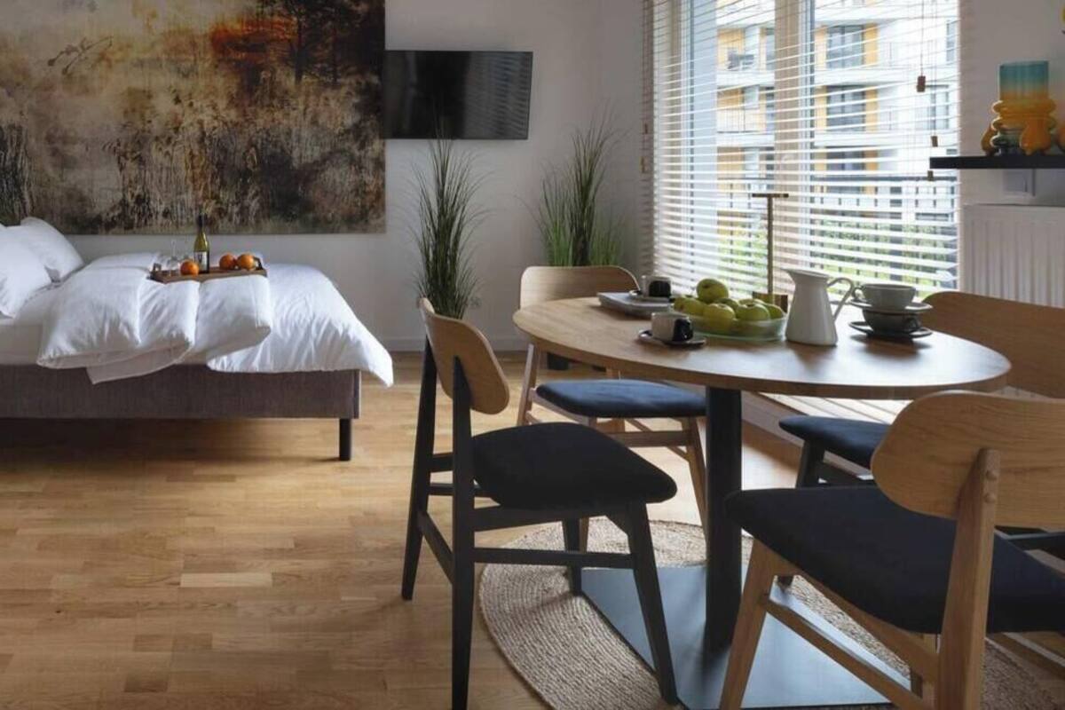 Quarto moderno com cama, mesa de cabeceira e área de refeições com cadeiras e uma mesa.