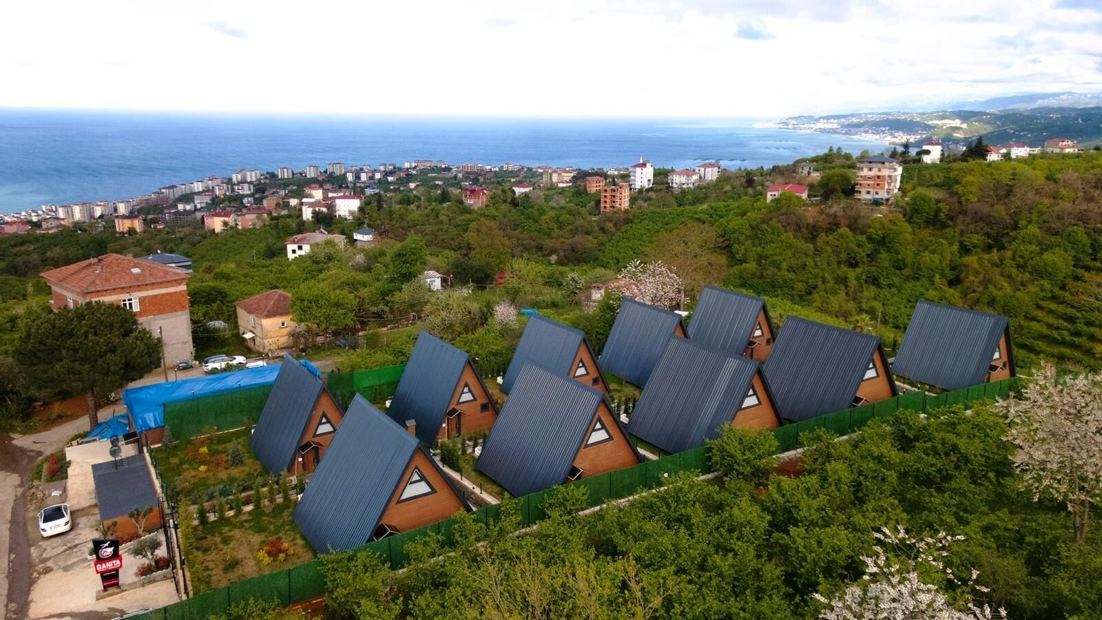 A coastal area with multiple houses, a swimming pool, and a view of the sea.