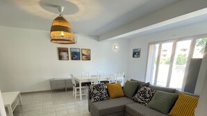 A modern living room with a grey sectional sofa, a fluffy grey rug, and a dining area with a white table and chairs. - House for 4, just 3 min from marina and beach (Sari-Solenzara)