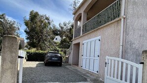 A two-story building with a balcony and a car parked in front. - House for 4, just 3 min from marina and beach (Sari-Solenzara)