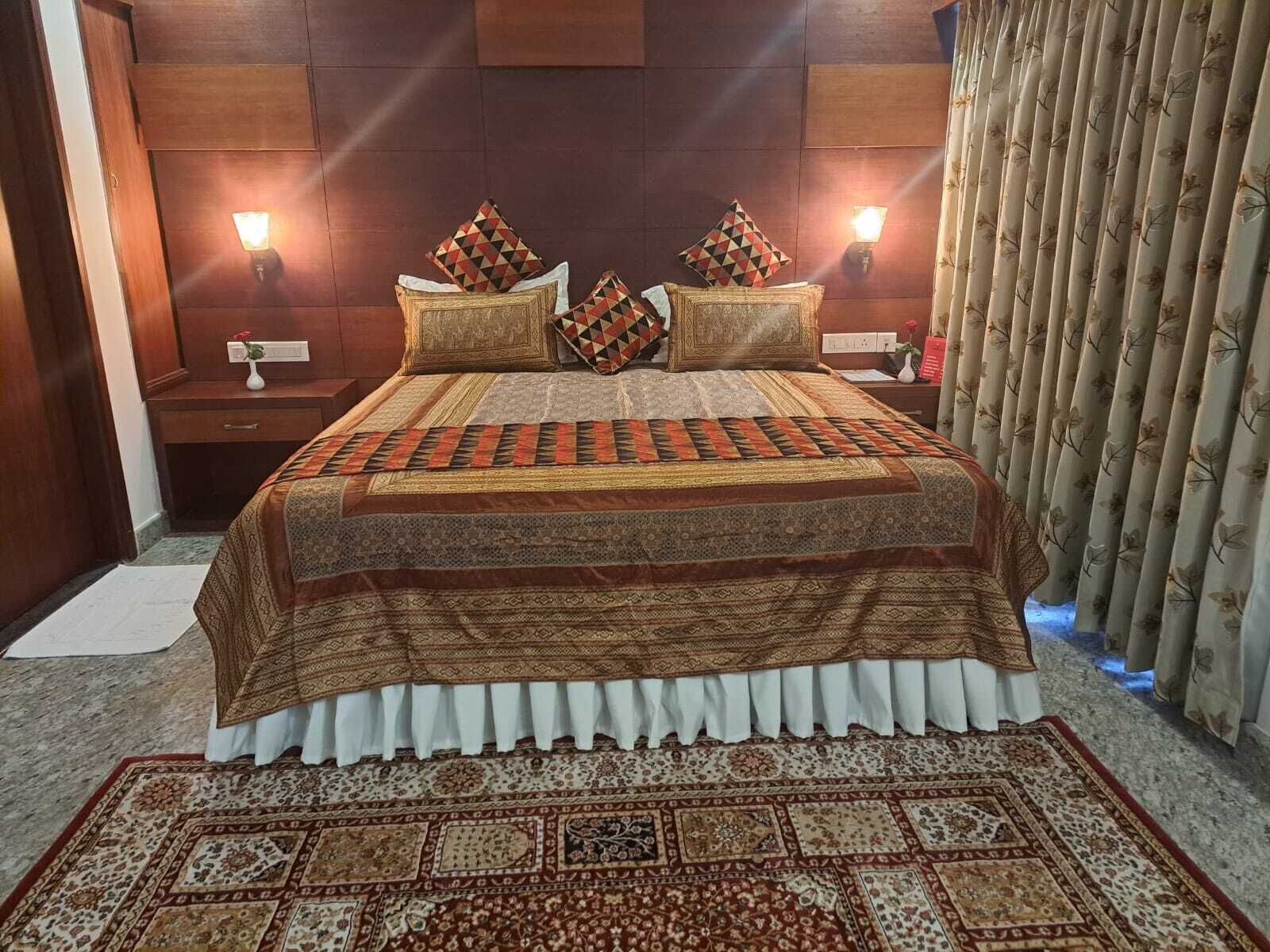 A bedroom with a large bed, two bedside tables, a nightstand, and a window with curtains.