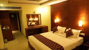 Une chambre d’hôtel avec un grand lit, un bureau, une chaise, un miroir et une table de chevet.