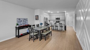 Une cuisine moderne avec des meubles blancs, un îlot central et un coin repas comprenant une table et des chaises.