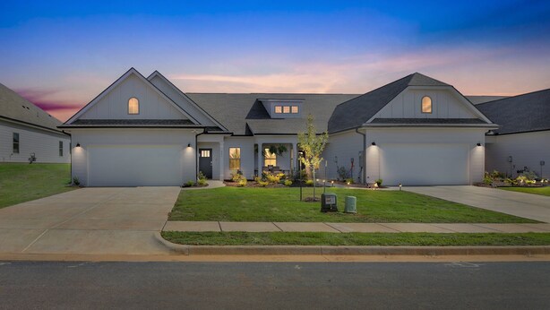 Une maison moderne avec un grand garage, une pelouse bien entretenue et une allée menant à l’entrée.