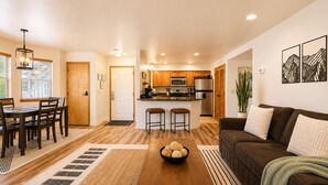 A modern kitchen with wooden cabinets, a central island, and bar stools. - Edelweiss Escape 1 Bedroom Condo (Leavenworth)