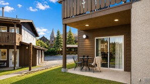 A residential building with a patio area, a covered outdoor seating space, and a large sliding glass door leading to a backyard. - Edelweiss Escape 1 Bedroom Condo (Leavenworth)